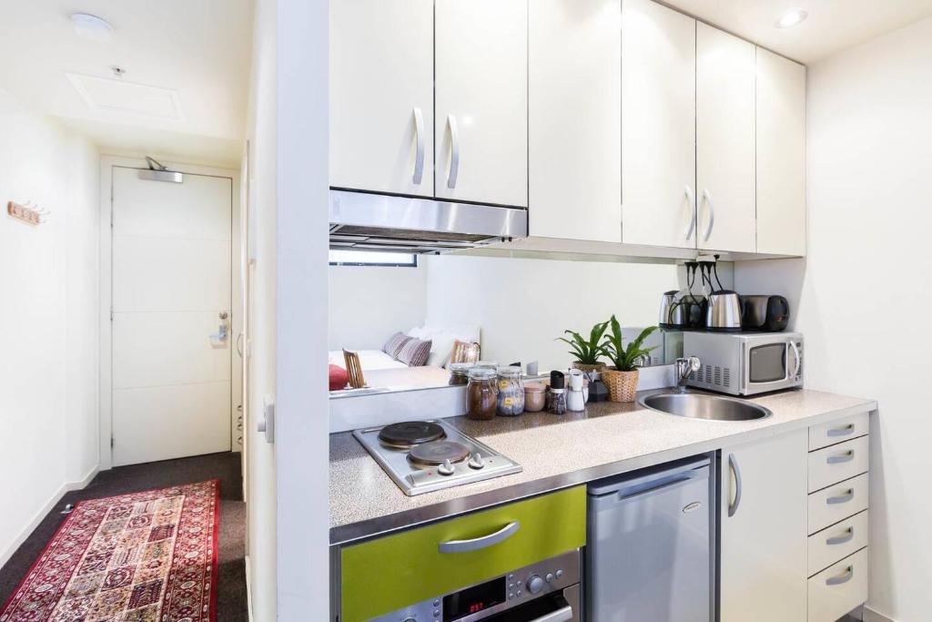 eine Küche mit weißen Schränken und einem Herd mit Backofen in der Unterkunft Simple on Swanston - A Central Student Accom Studio in Melbourne