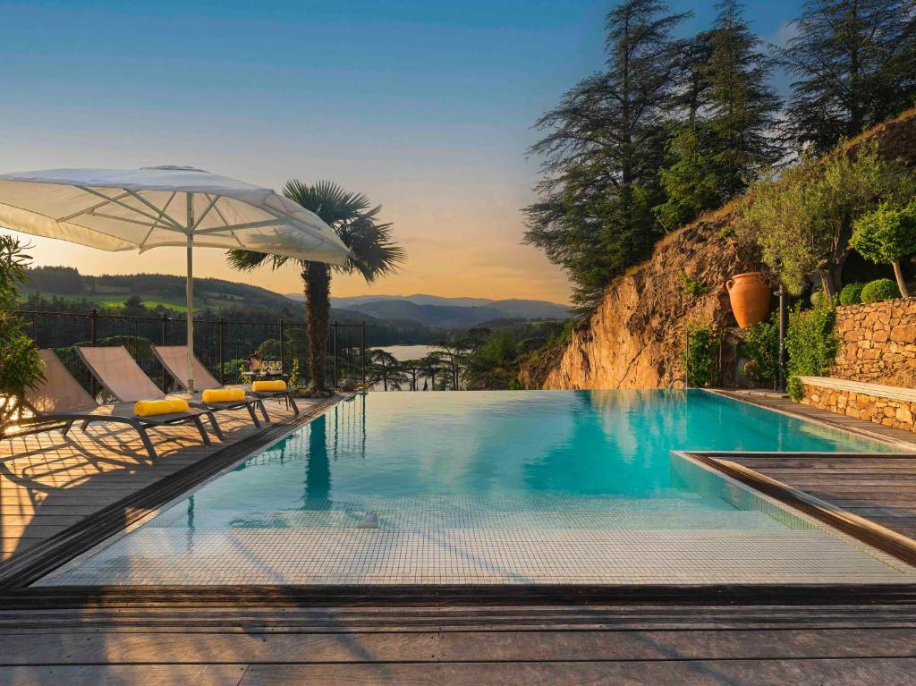 a swimming pool with chairs and an umbrella at Auberge Du Lac in Saint-Marcel-lès-Annonay