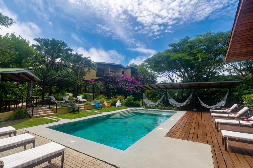 a swimming pool in a yard with chairs and a house at Rinconcito Lodge in Hacienda Santa María