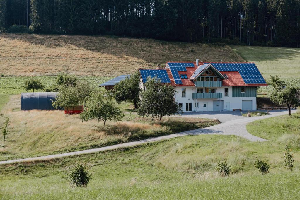 una casa con paneles solares en la parte superior de un campo en BodenSEE Apartment Neukirch Goppertsweiler FUCHS, en Neukirch