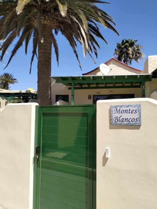 a green door with a sign on it next to a house at Montes Blancos in Costa Calma