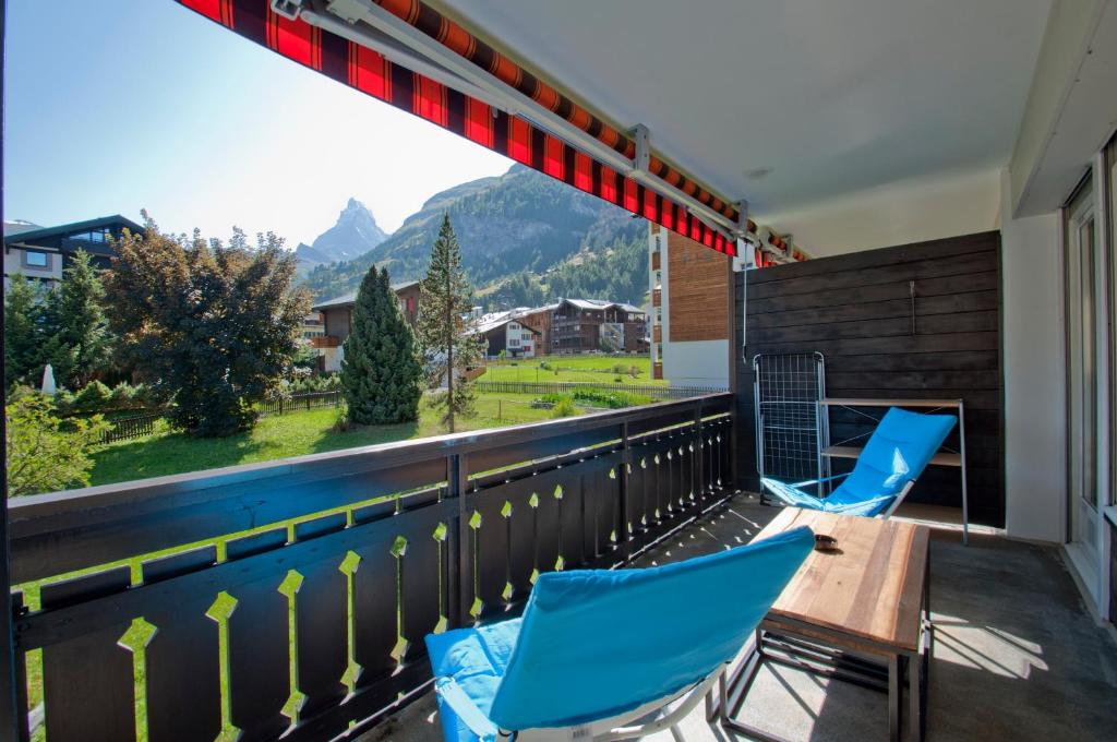 einen Balkon mit blauen Stühlen, einem Tisch und Aussicht in der Unterkunft Haus Matten, Apartment Breithorn in Zermatt