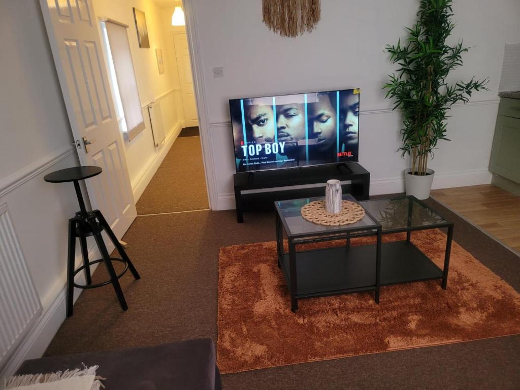 a living room with a flat screen tv and a table at Nariken Apartments in Bristol