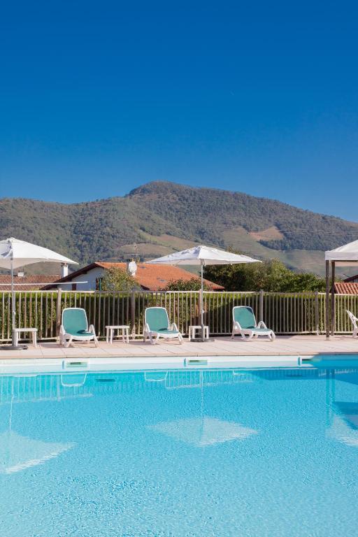une piscine avec chaises et parasols dans l'établissement VVF Résidence Pays Basque Saint-Jean-Pied-de-Port, à Saint-Jean-Pied-de-Port