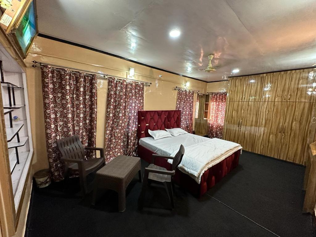 sypialnia z łóżkiem, krzesłami i zasłonami w obiekcie Aubiz Villa w mieście Śrinagar