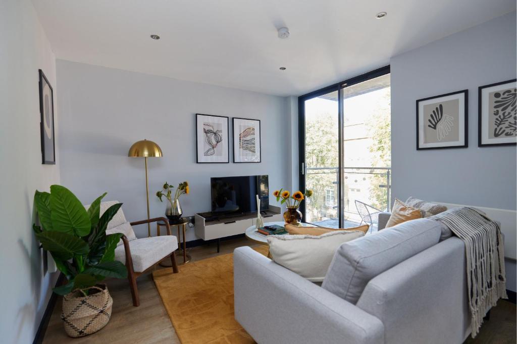 a living room with a white couch and a tv at The Whitechapel Place - Stunning 2BDR Flat with Balcony in London