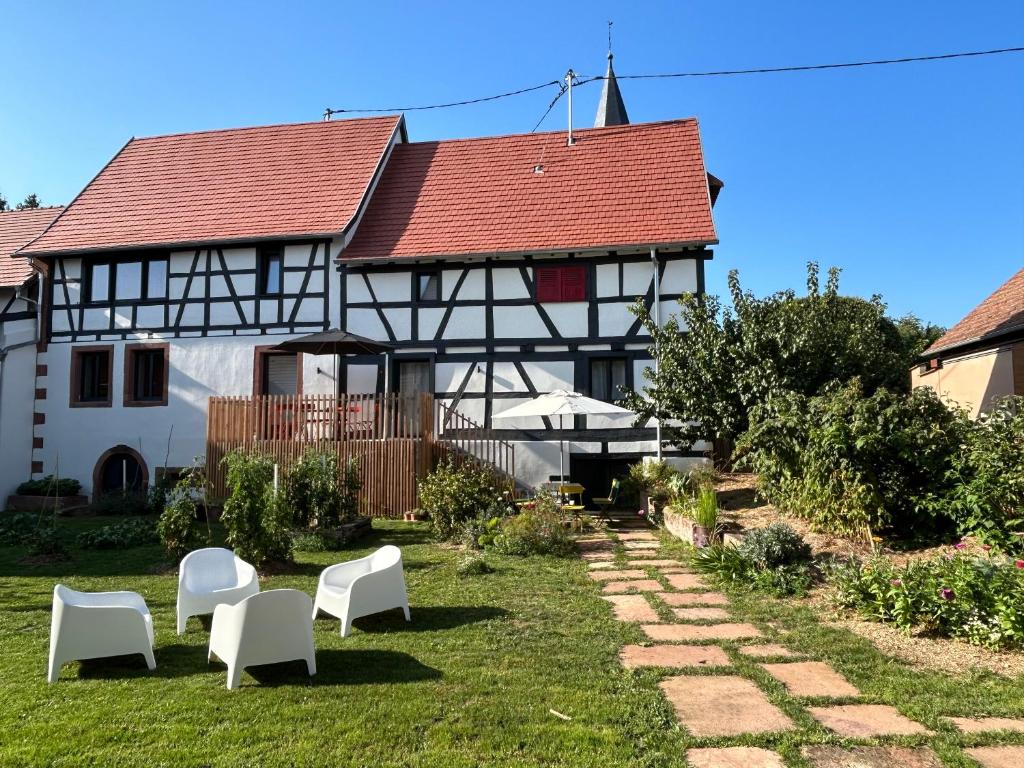 ein Haus mit weißen Stühlen und einem roten Dach in der Unterkunft Corps de ferme alsacien in Grassendorf