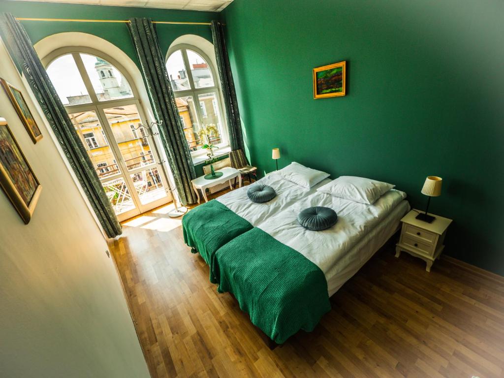 a green bedroom with a bed and a large window at Hostel Pod Basztą in Lublin