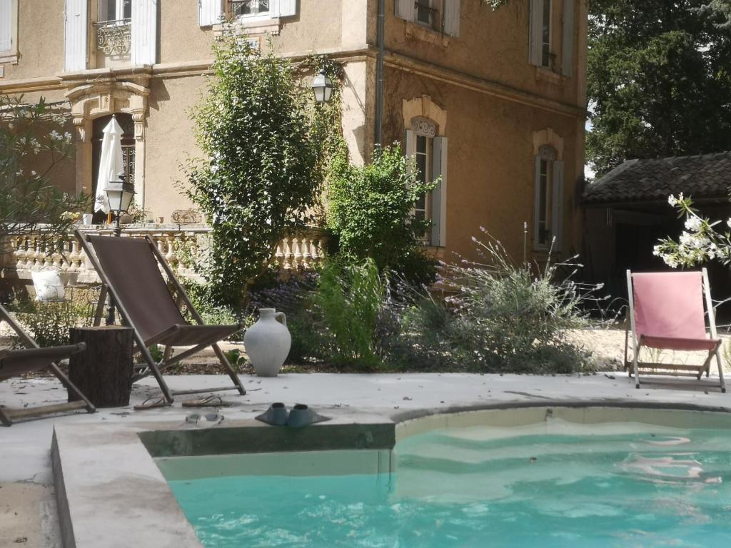 a swimming pool with two chairs and a house at B&B Maison Felisa in Sabran