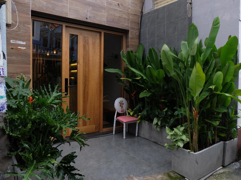 a chair sitting in front of a door with plants at HALF Coffee N Dorm in Ho Chi Minh City