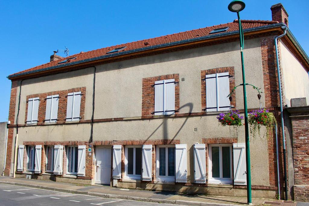 um edifício de tijolos com janelas brancas numa rua em La demeure du maréchal-ferrant em Pierry