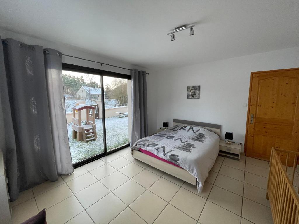1 dormitorio con cama y ventana grande en Grand gite peyrau aubrac loup gévaudan lozère A75, en Aubigeyres