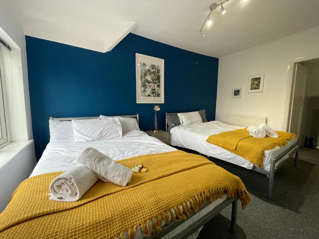 2 camas en una habitación con una pared azul en HUGE Apartment - 12min to City - FREE parking - Contractor Friendly - IRWELL STAYS en Mánchester