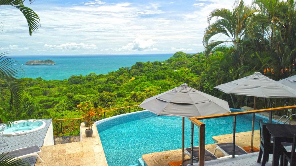 a swimming pool with umbrellas and a view of the ocean at Villa Roca Boutique Resort & Suites - ADULT ONLY in Manuel Antonio