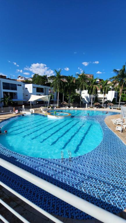 a large swimming pool with blue water and palm trees at Apartasol Santa Fe de Antioquia - Ciudadela Santa Fe in Santa Fe de Antioquia