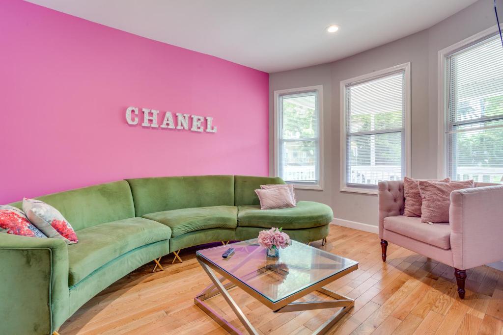 a living room with a green couch and a pink wall at Vibrant East Orange Townhome Near Red Bull Arena! in East Orange