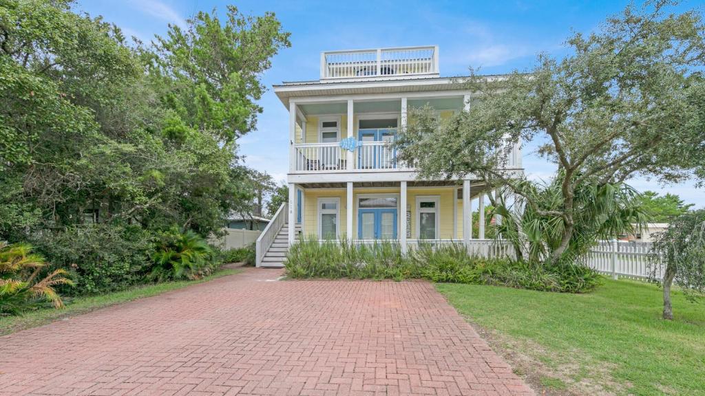 a large yellow house with a brick driveway at Seashine and Sunkises - Great pricing near Seaside in Santa Rosa Beach