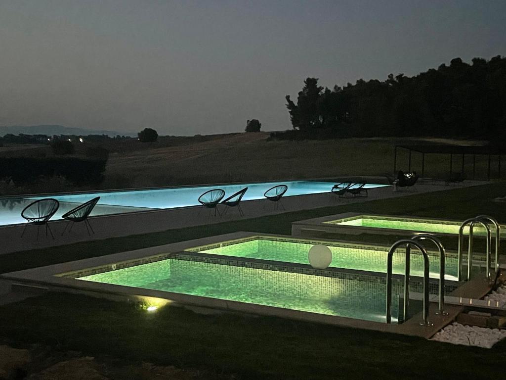 ein großer Pool in der Nacht mit Lichtern darin in der Unterkunft Oikos Sani Suites in Sani Beach