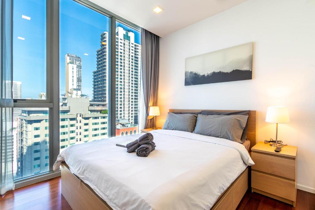 a bedroom with a large bed and a large window at Hyde Sukhumvit 11 Branded Suites in Bangkok