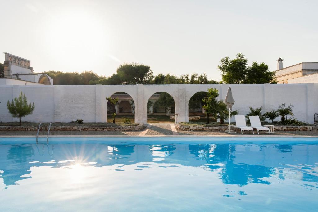 a swimming pool with blue water in front of a building at Masseria Gorgognolo in Ostuni