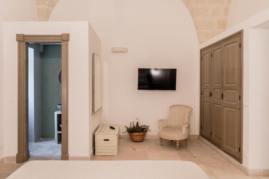 a living room with a chair and a tv on a wall at Masseria Gorgognolo in Ostuni
