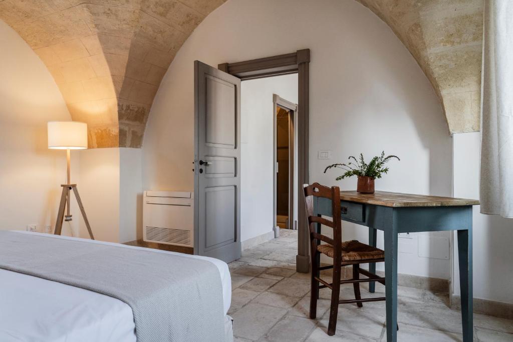 a bedroom with a bed and a table and a desk at Masseria Gorgognolo in Ostuni