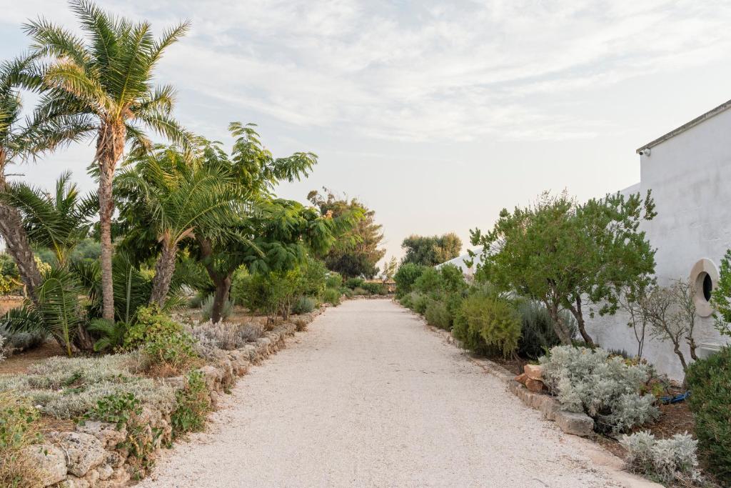 a dirt road with palm trees and a building at Masseria Gorgognolo in Ostuni