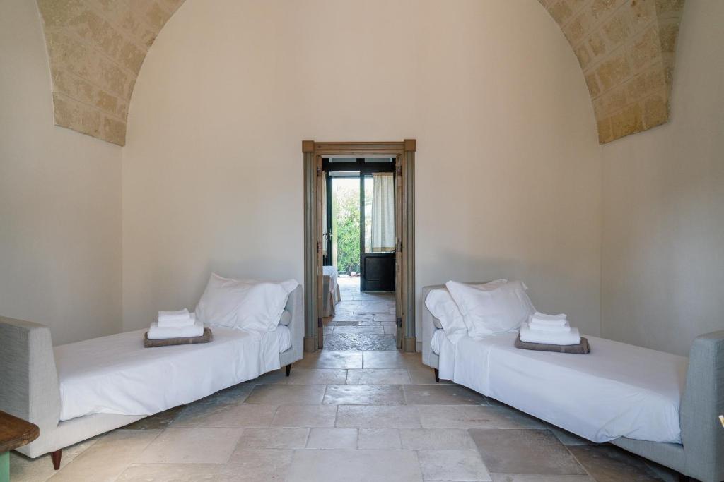two beds in a room with a hallway at Masseria Gorgognolo in Ostuni