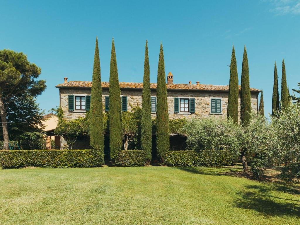 a house with trees in front of a yard at Rustic Farmhouse in Cortona with Swimming Pool in Cortona