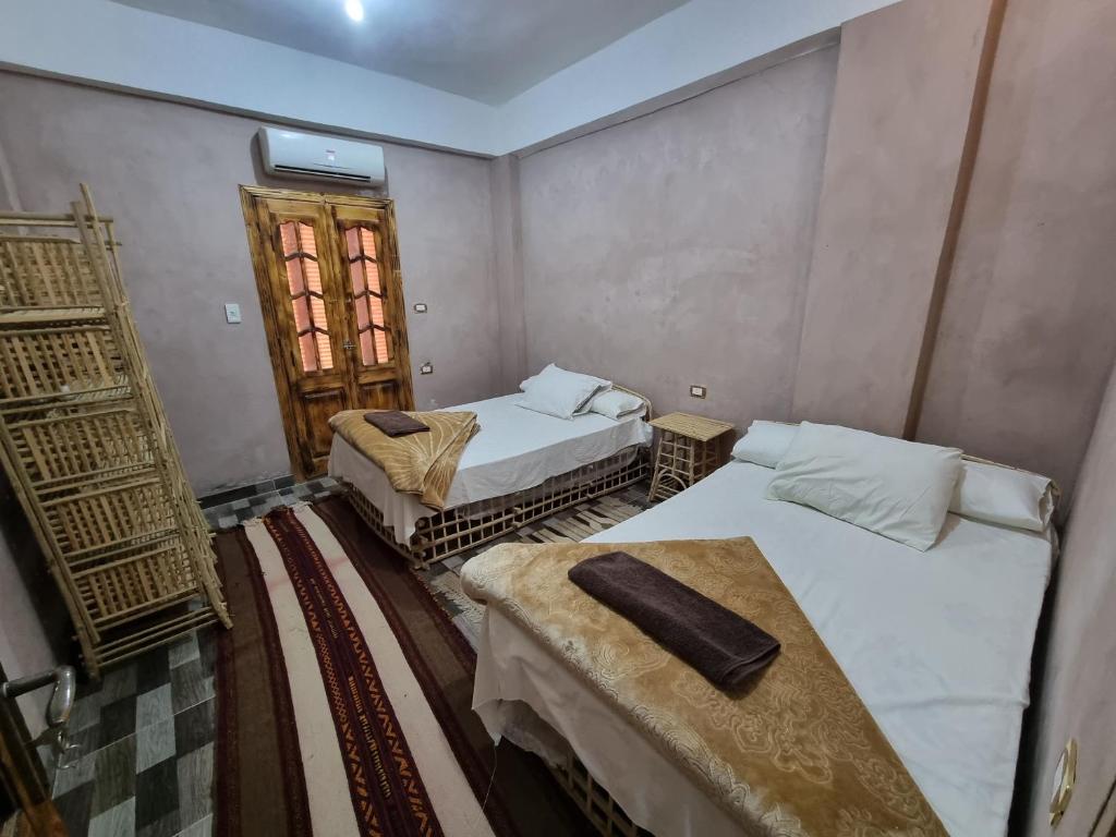 Cette chambre comprend 2 lits, une table et une porte. dans l'établissement quiet home, à Siwa