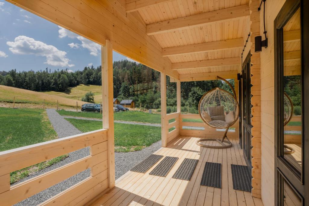 - une terrasse couverte en bois avec une chaise en osier dans l'établissement Górna Kudowa Domki Wypoczynkowe, à Kudowa-Zdrój