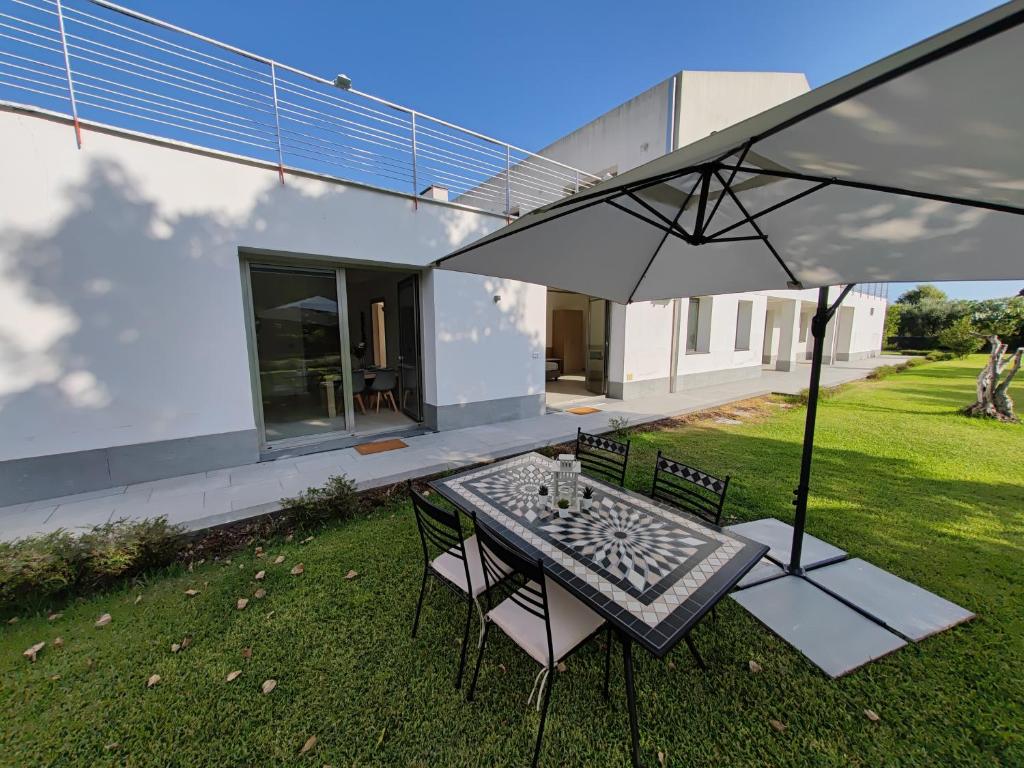 a patio with a table and chairs and an umbrella at Villa Persea in Santa Venerina