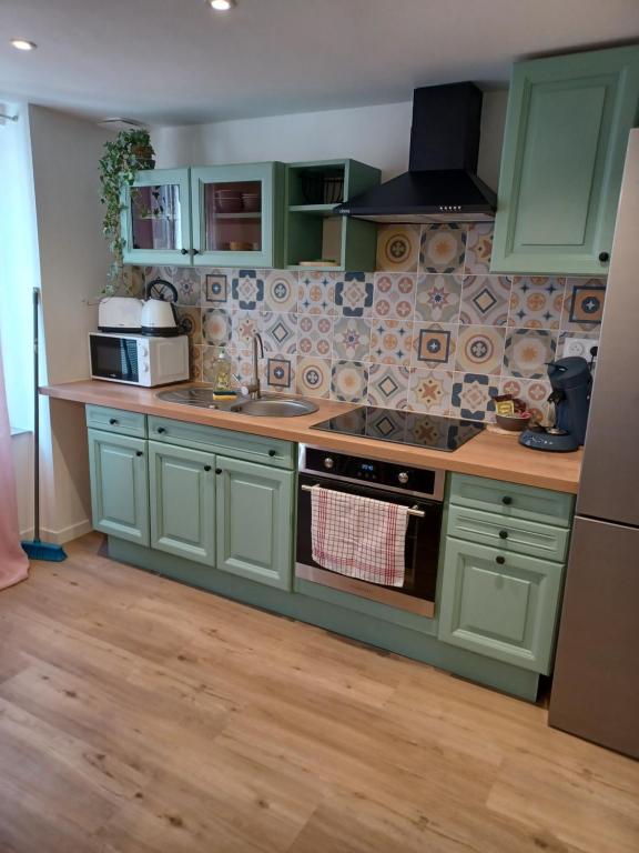 une cuisine avec des armoires vertes et une cuisinière four supérieur dans l'établissement Duplex centre ville, à Ernée