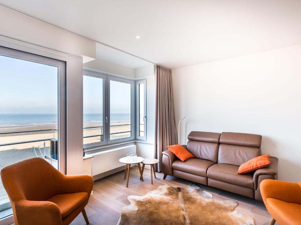 a living room with a couch and a large window at Modern luxury new build apartment on the Zeedijk in Koksijde