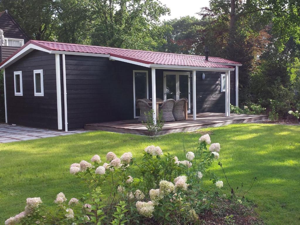 um barracão preto com um deque num quintal em Garden View chalet with terrace or conservatory near Amerongse Berg em Elst