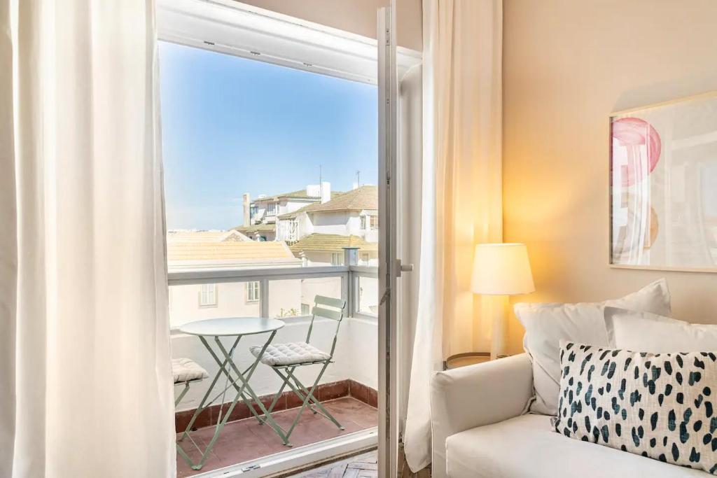 a living room with a couch and a balcony with a table at Prior23 in old town 4min from beach w/ terrace in Cascais
