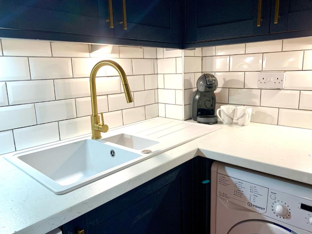 Il comprend une cuisine équipée d'un évier et d'un lave-vaisselle. dans l'établissement Bright modern flat in central Twickenham, à Twickenham
