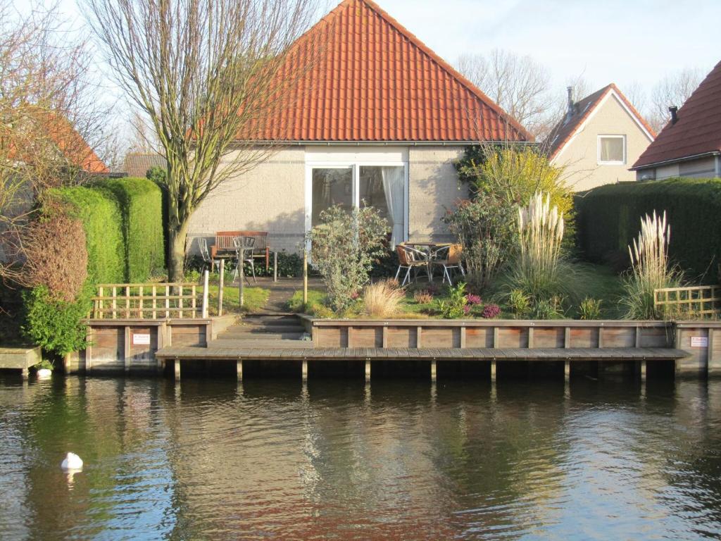 a house with a dock next to a body of water at Detached bungalow with dishwasher at the water in Medemblik