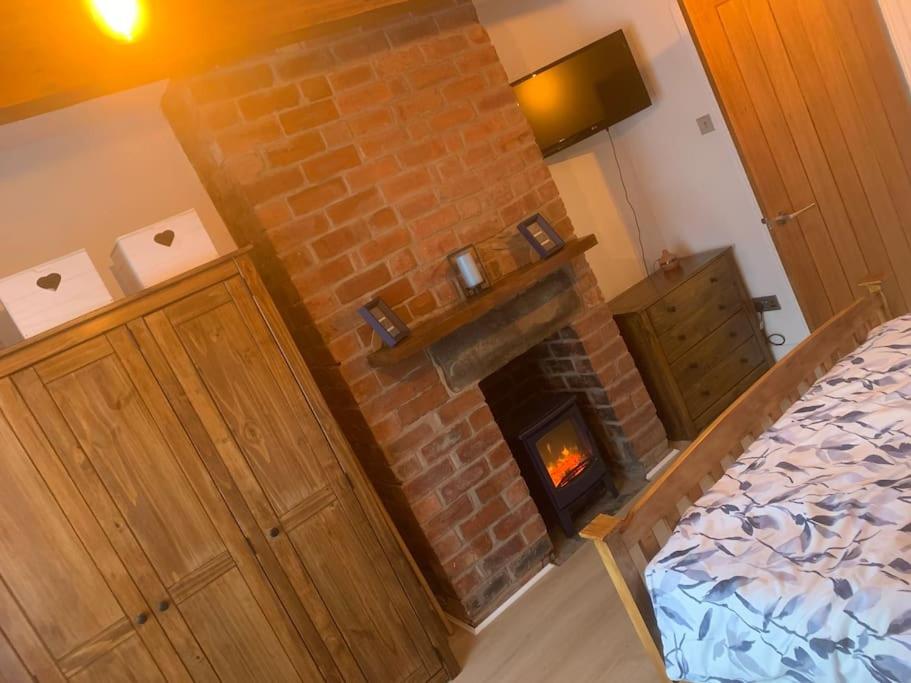 a brick fireplace in a bedroom with a bed at Quaint 1 bedroom cottage in Pudsey, Leeds in Pudsey