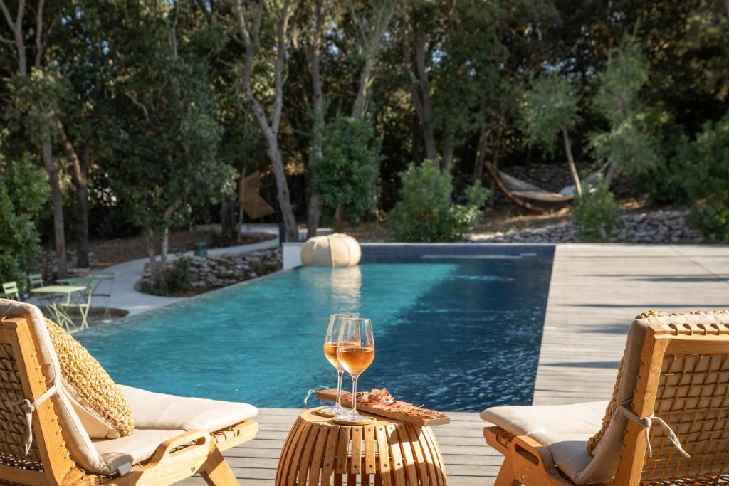 un bicchiere di vino seduto su un tavolo accanto alla piscina di Aria Cigala a Bonifacio