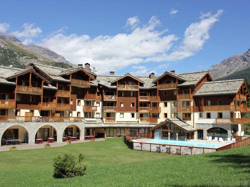 ein großes Resortgebäude mit einem Pool im Hof in der Unterkunft Rustic apartment on the slopes in cozy Val Cenis in Lanslebourg-Mont-Cenis