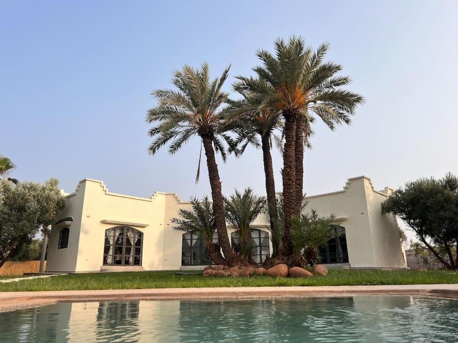 a house with palm trees in front of a swimming pool at Villa Daïs in Marrakesh