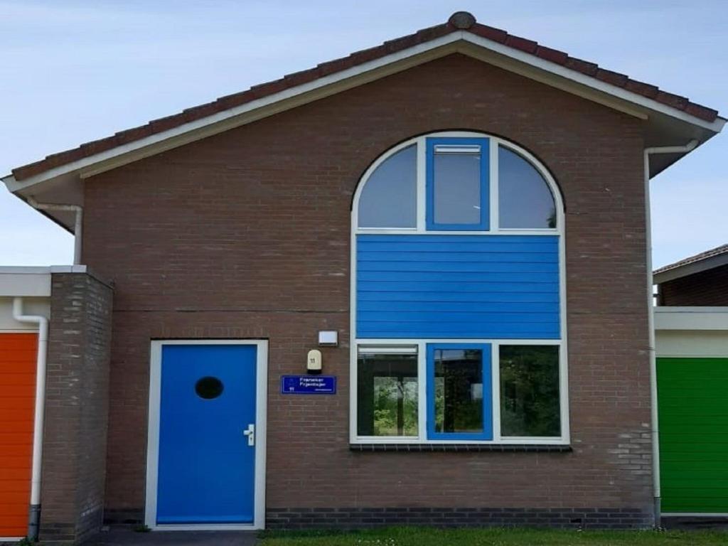 Semi detached house in Franeker with a shared pool في فرانيكير: منزل فيه باب ازرق ونافذة
