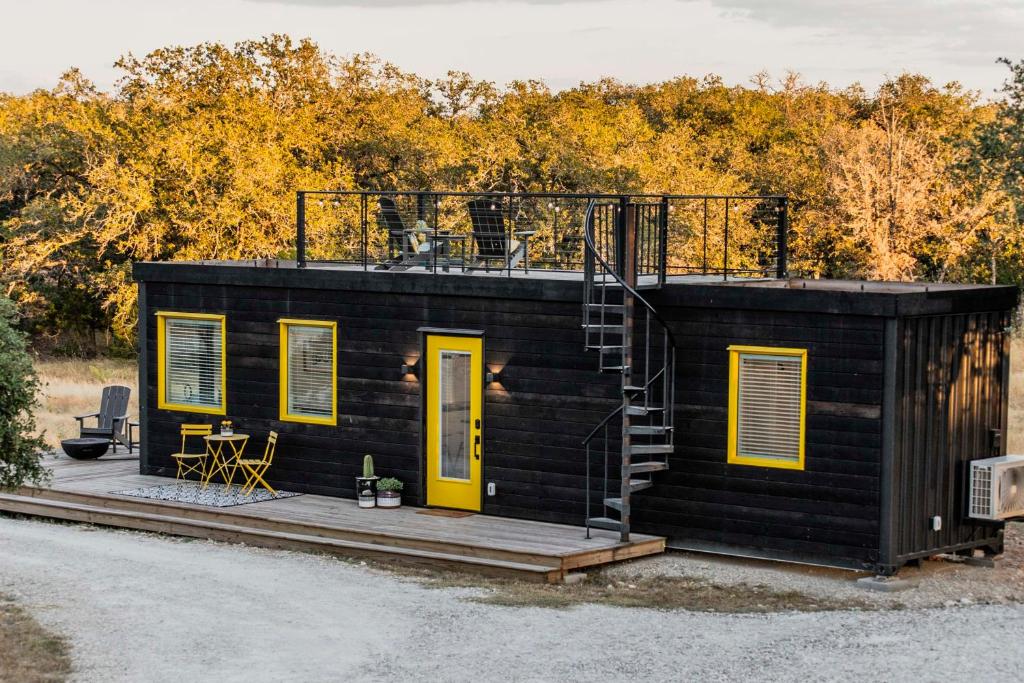 a black tiny house with yellow doors and a deck at New The Yellow Beacon-Luxury Shipping Container in Fredericksburg