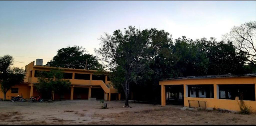 a yellow building with a tree in front of it at Hotel Regina “El Llano” in Cosalá