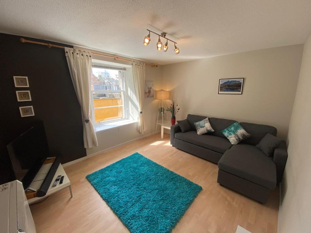 a living room with a couch and a blue rug at Lombard Hide Away in Inverness