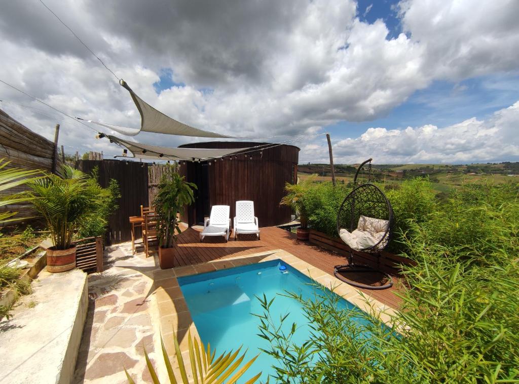 a backyard with a swimming pool and a deck with chairs at Barichara Glamping in Barichara