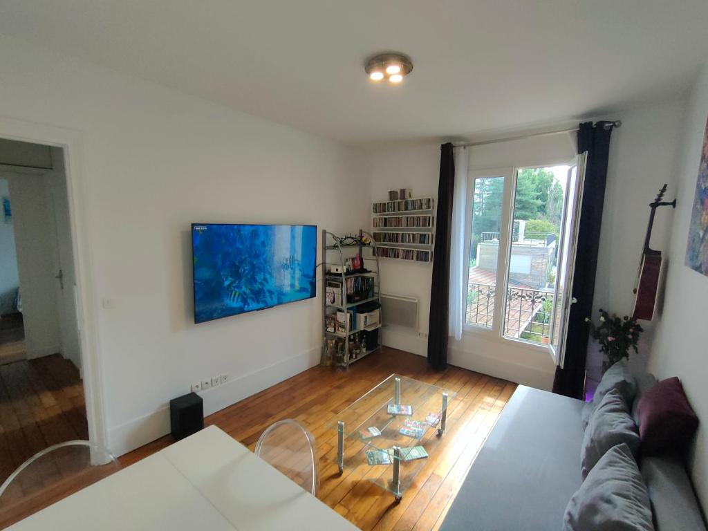 a living room with a couch and a tv on a wall at Bel appartement Paris Ouest sur cour proche métro in Boulogne-Billancourt