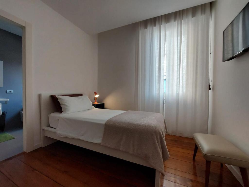 a white bedroom with a bed and a window at Casa del Corso in Pordenone