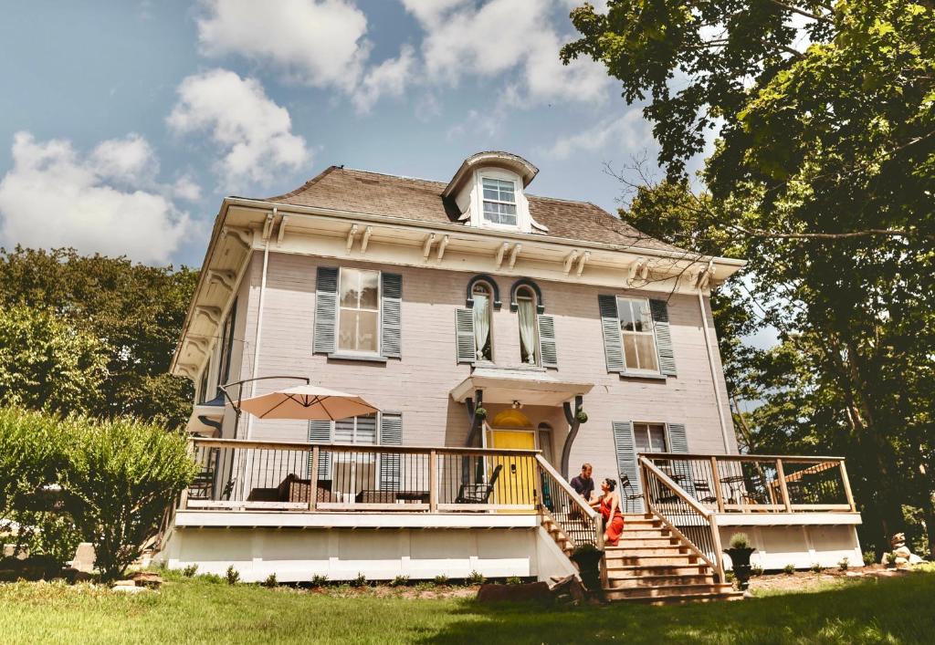 an old house with people standing on the front porch at The Montague Rose Inn & Cafe in Saint Andrews